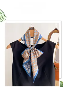 Close-up of sky blue and tan paisley silk scarf tied in a bow on a black dress