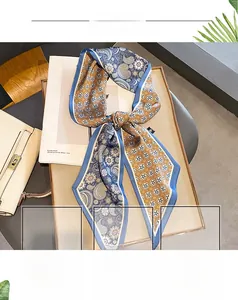 Close-up of silk-like paisley scarf tied in a bow on a magazine and wooden tray