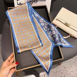 Double-sided paisley and geometric silk scarf displayed on a metallic tray