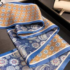 Luxurious double-sided paisley silk scarf in navy and gold draped on a display tray