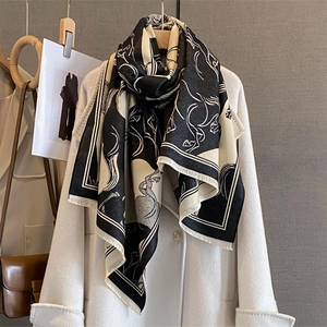 Scarf with running horse print and fringe trim styled on a white coat for winter