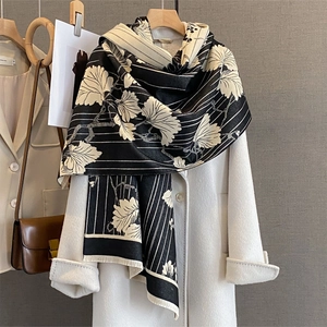 Détail d'une écharpe à motifs de feuilles de ginkgo noir et beige avec des franges