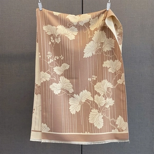 Détail de motifs de feuilles élégants et de fines franges sur une écharpe caramel