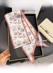 Detail of pink floral silk scarf featuring fine stitching and vibrant flower patterns