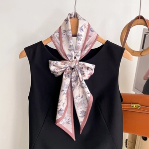 Floral print silk scarf styled as a bow on a black dress with an elegant purple finish