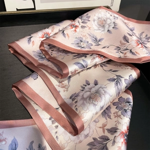 Elegant floral silk scarf with pink and orange patterns on a premium satin surface