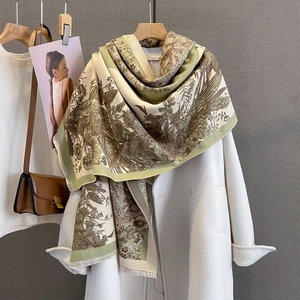 Detail of vintage gray-green scarf with floral prints and fringe on white coat