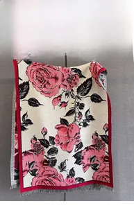 Close-up of red rose floral print on beige pashmina shawl with grey fringe detail