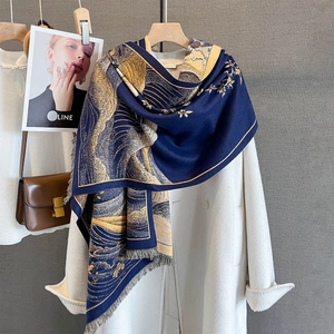 Scialle tipo cashmere blu e oro con stampa loto e onde e nappe su cappotto bianco