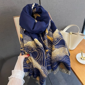 Dettaglio di sciarpa pashmina blu navy con motivi a onde dorate e frange grigie