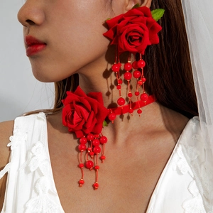 Detailed view of red rose choker with long beaded tassels on white lace bridal dress