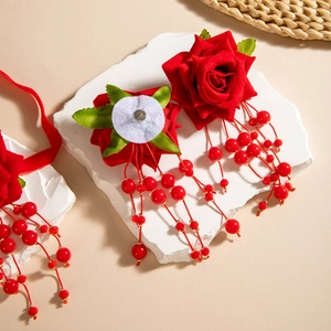 Detailed close-up of red fabric rose hair clip with beaded tassels on stone stand
