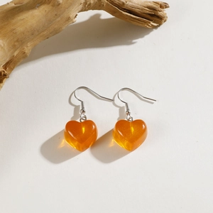 Close-up of translucent amber heart pendant earrings with sparkling gold dust detail