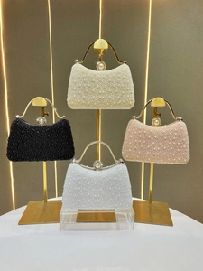 Elegant pearl evening handbags in four colors with gold metal handles on luxury display