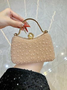 Detail of elegant pearl evening bag with gold metal handle held by a model