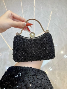 Detail of black beaded evening bag with golden handle and large pearl clasp