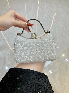 Detailed macro of elegant pearl evening bag with silver curved metal handle and clasp