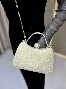 Detail view of pearl evening bag with gold chain strap on black velvet dress