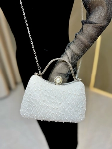 Detail of white pearl evening bag with silver metal handle and chain strap for women