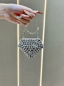 Detail of a luxury mini diamond-shaped lipstick bag with silver rhinestones and chain