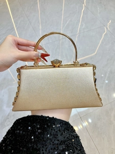 Macro view of gold evening clutch featuring rhinestone petal buckle and metallic handle