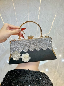 Detail of luxury evening clutch bag featuring 3D metallic flowers and rhinestone patterns