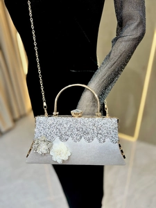 Detail of silver evening clutch bag featuring 3D flowers and sparkling rhinestone texture