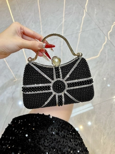 Macro shot of white bead starburst on black beaded evening bag with gold handle