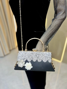 Close-up of rhinestone evening bag featuring 3D floral accents and a gold metal handle