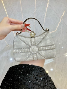 Macro shot of elegant pearl evening bag with ornate silver metal handle and clasp