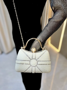 Detailed close-up of pearl evening bag featuring radial pearl inlay and gold metal handle