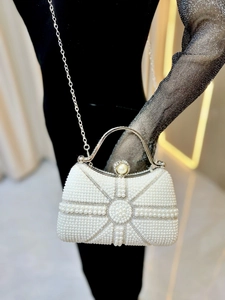 Detail of white pearl evening bag with silver metal handle and detachable chain strap