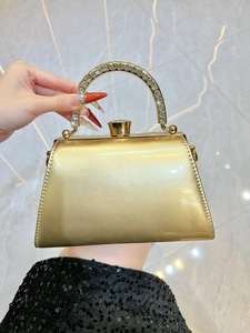 Close-up of luxury gold evening clutch with rhinestone handle and jewel-shaped clasp