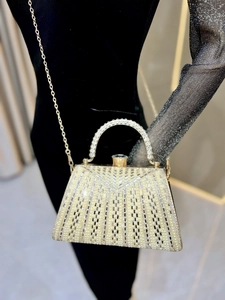 Detail of luxury evening clutch with white pearls, crystals, and gold chain strap