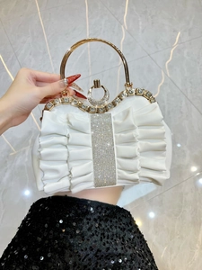 Detail of white pleated evening bag with sparkling rhinestone strip and gold metal ring handle