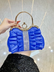 Macro view of bright blue pleated evening bag with sparkling rhinestones and gold metal handle