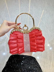 Close-up of red ruffled evening bag with gold circular handle and sparkling rhinestones
