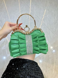 Detail of green pleated evening bag with sparkling rhinestone stripes and golden handle