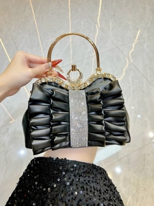 Detail of black pleated evening bag with sparkling diamond trim and gold handle