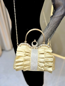 Close-up of gold pleated evening clutch with sparkling rhinestones and metal handle