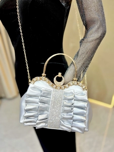 Macro detail of pleated evening clutch with crystal-encrusted handle and secure buckle