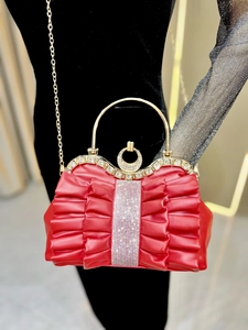 Close-up of pleated red evening bag with diamond embellishments and gold circular handle