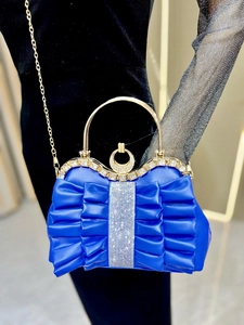 Detail of blue pleated evening bag with sparkling rhinestones and gold round handle