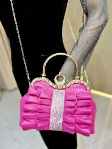 Macro view of pleated fuchsia bow evening bag with sparkling rhinestones and gold handle