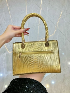 Detail of gold snakeskin pattern handbag with woven handle and back zipper pocket