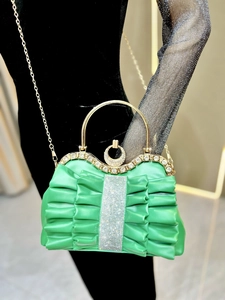 Detail of emerald green pleated satin evening bag with rhinestone buckle and gold ring handle