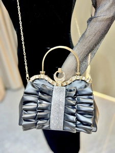 Detail of black pleated evening bag with sparkling rhinestone accents and gold ring handle