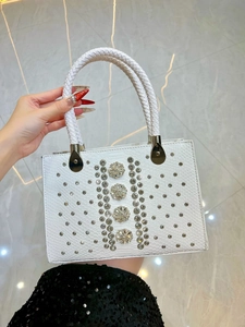 Close-up of white snakeskin texture handbag with floral crystal buckles and woven handle