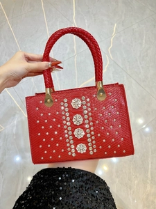 Macro detail of red snakeskin texture handbag with sparkling rhinestone flower embellishments