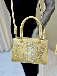 Detail of luxury gold embossed leather bag with sparkling crystal flowers and handles